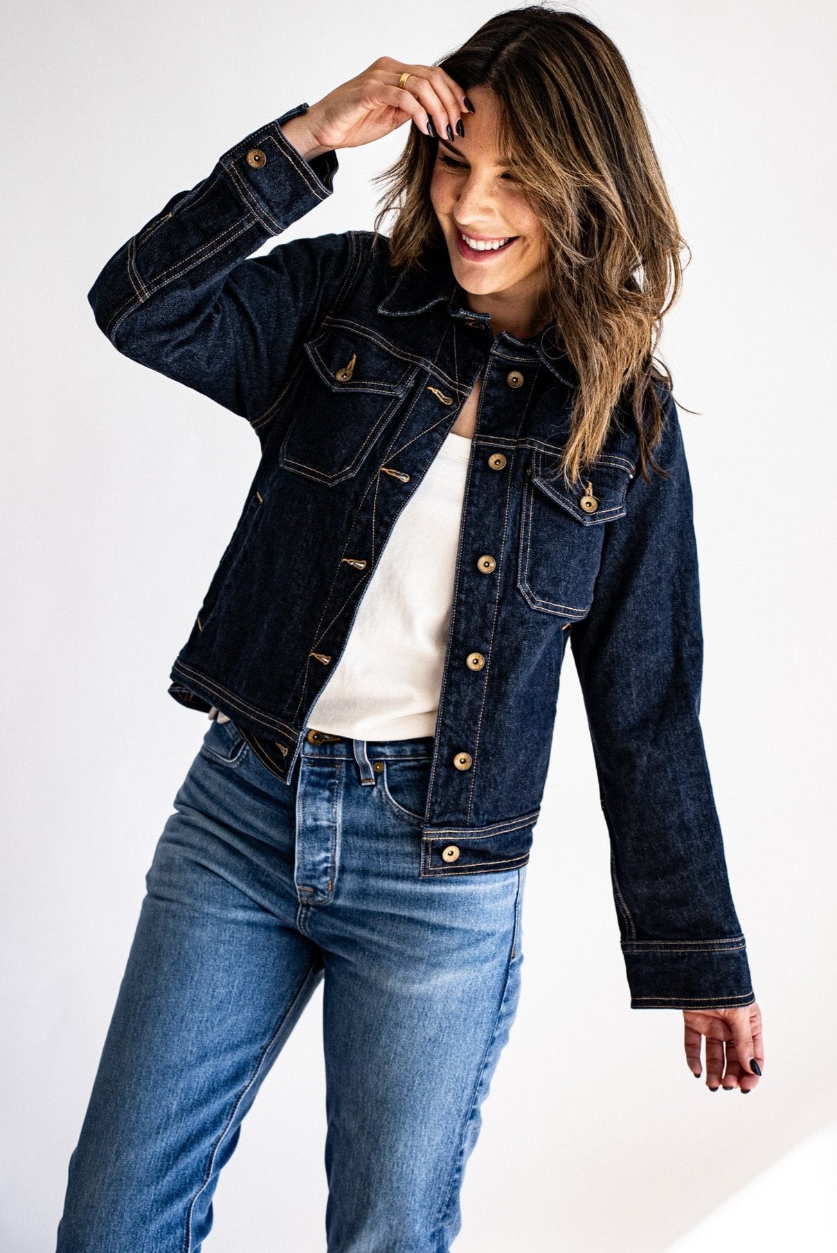 dark USA made denim jacket paired with light-wash jeans and a white shirt, styled casually with a bright background.