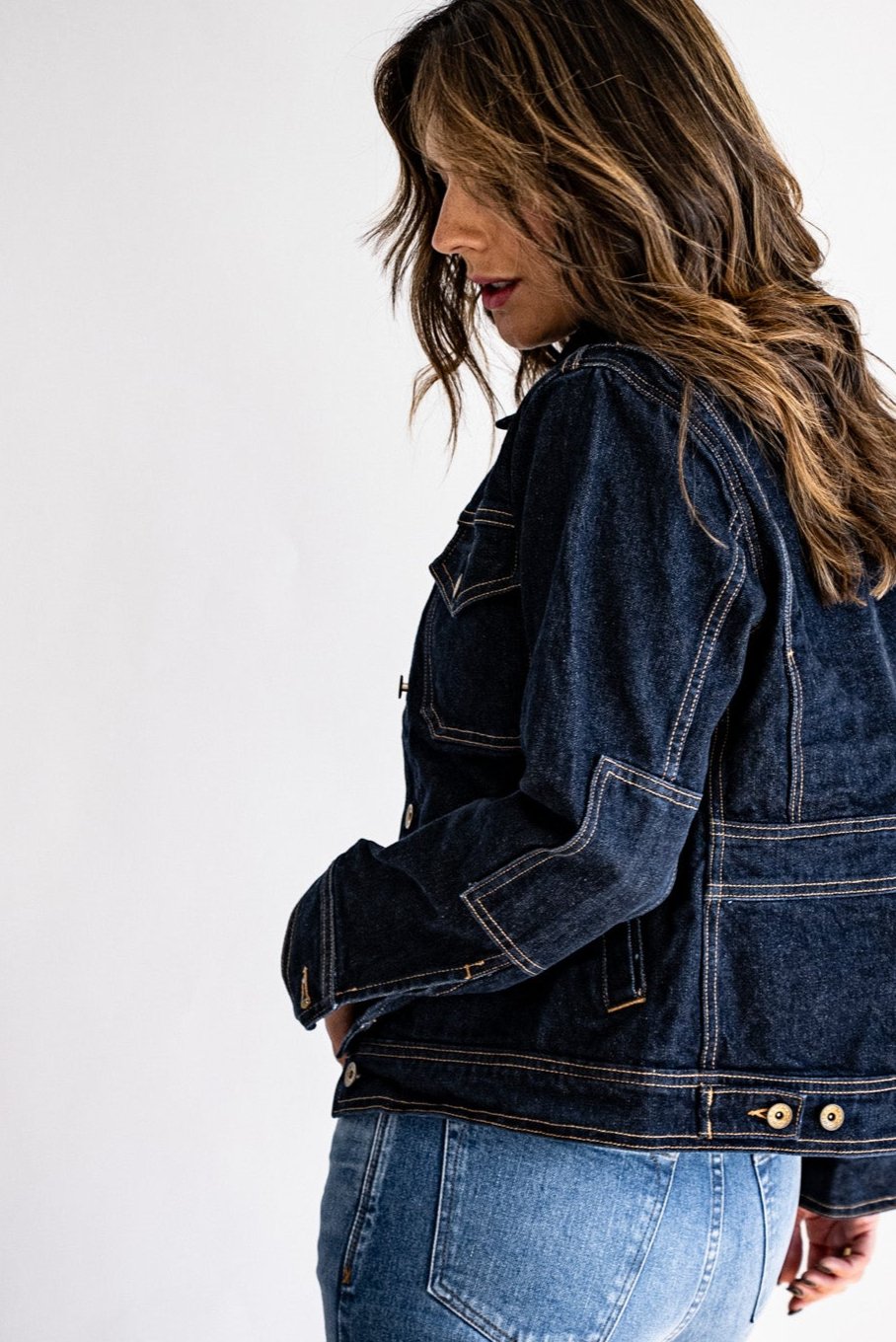 Trucker jacket made in USA styled with light blue jeans, modeled from a side profile against a white background.