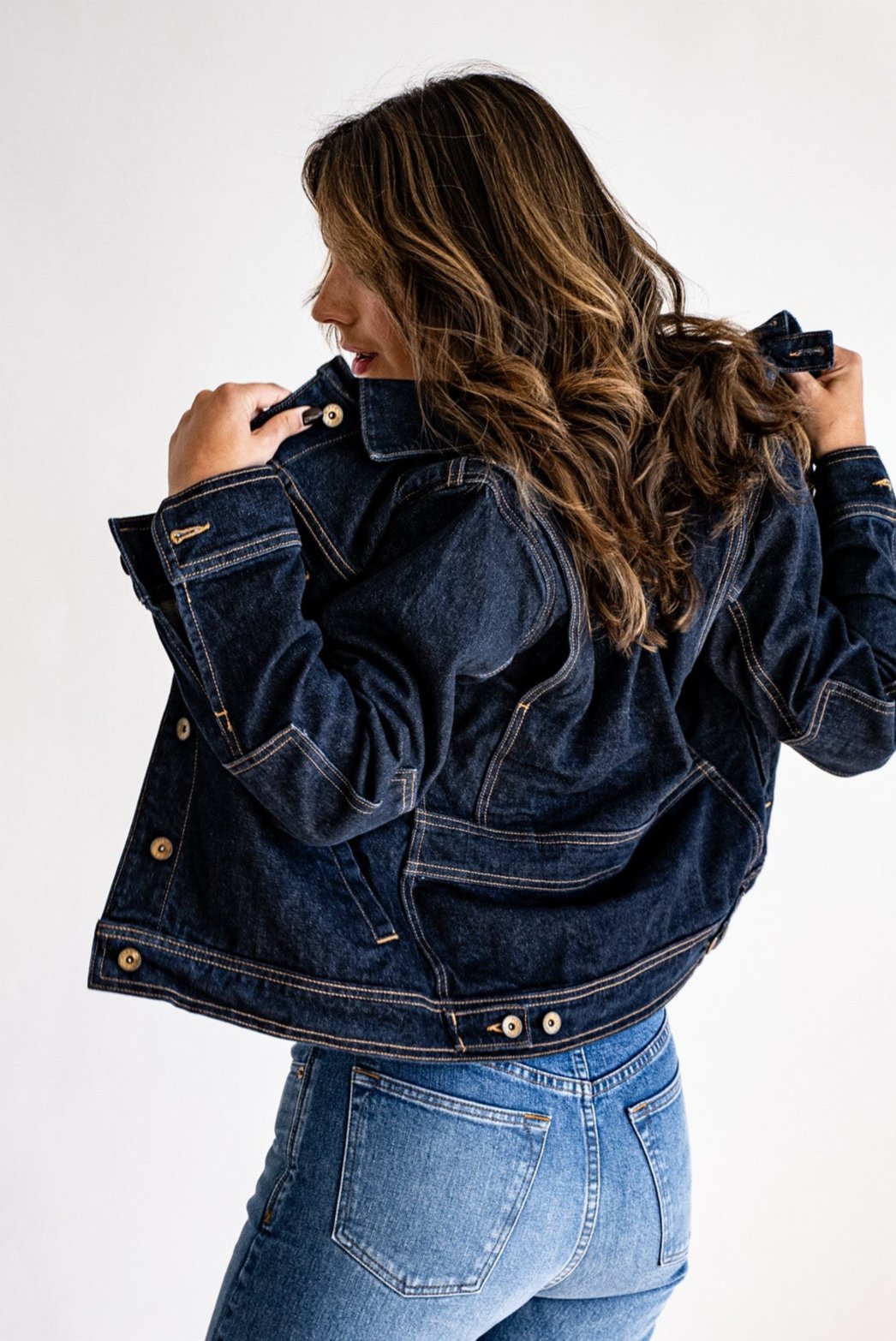 Dark denim jacket made in USA paired with light blue jeans, modeled from the back against a white background.