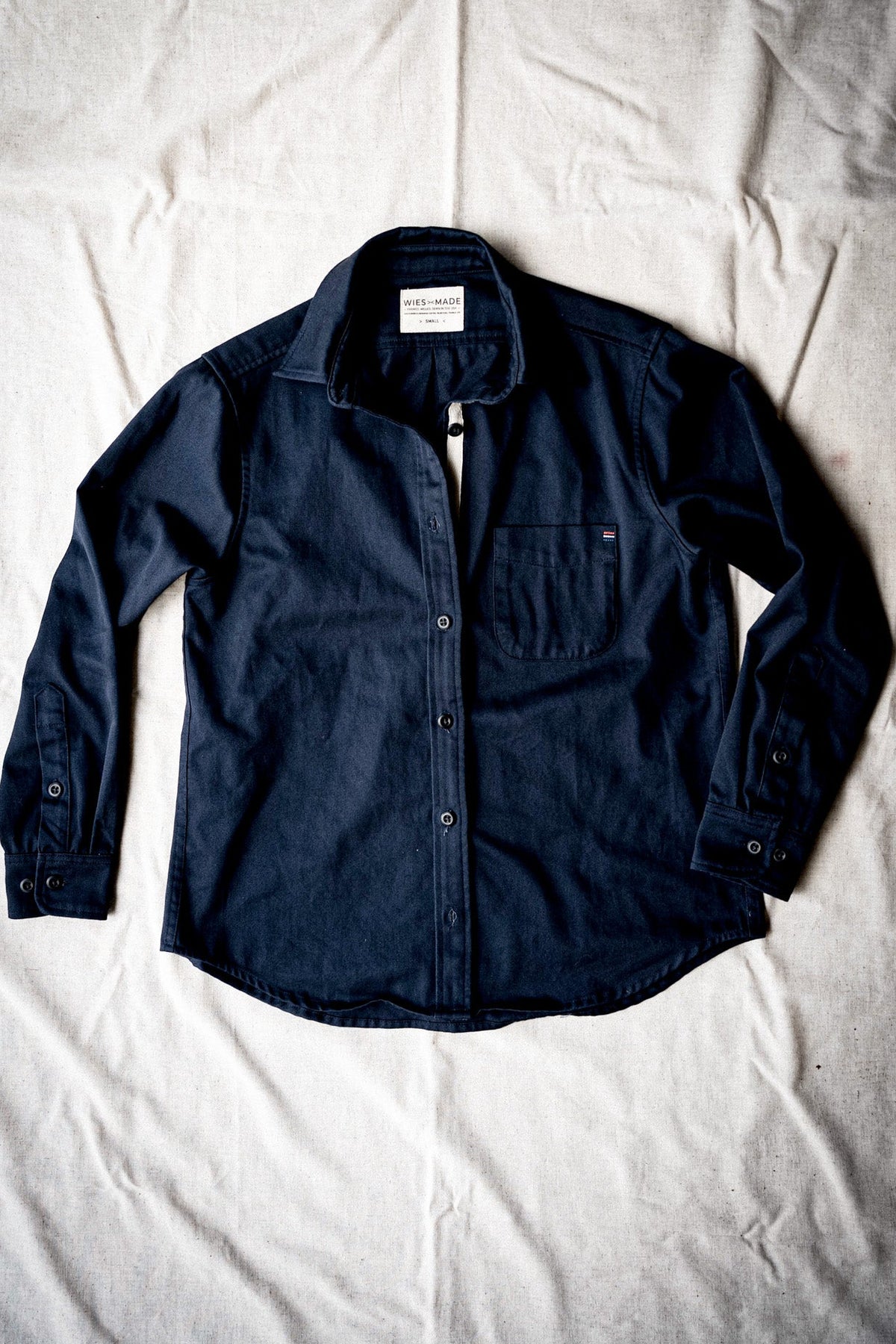 Women's navy cotton work shirt laid flat, showing the button front, chest pocket and long sleeves.