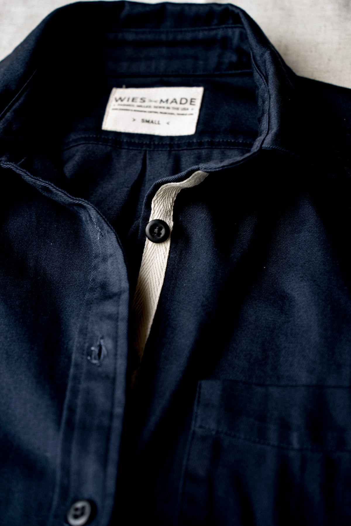 Collar, woven label and button placket detail on a women's American made navy shirt.