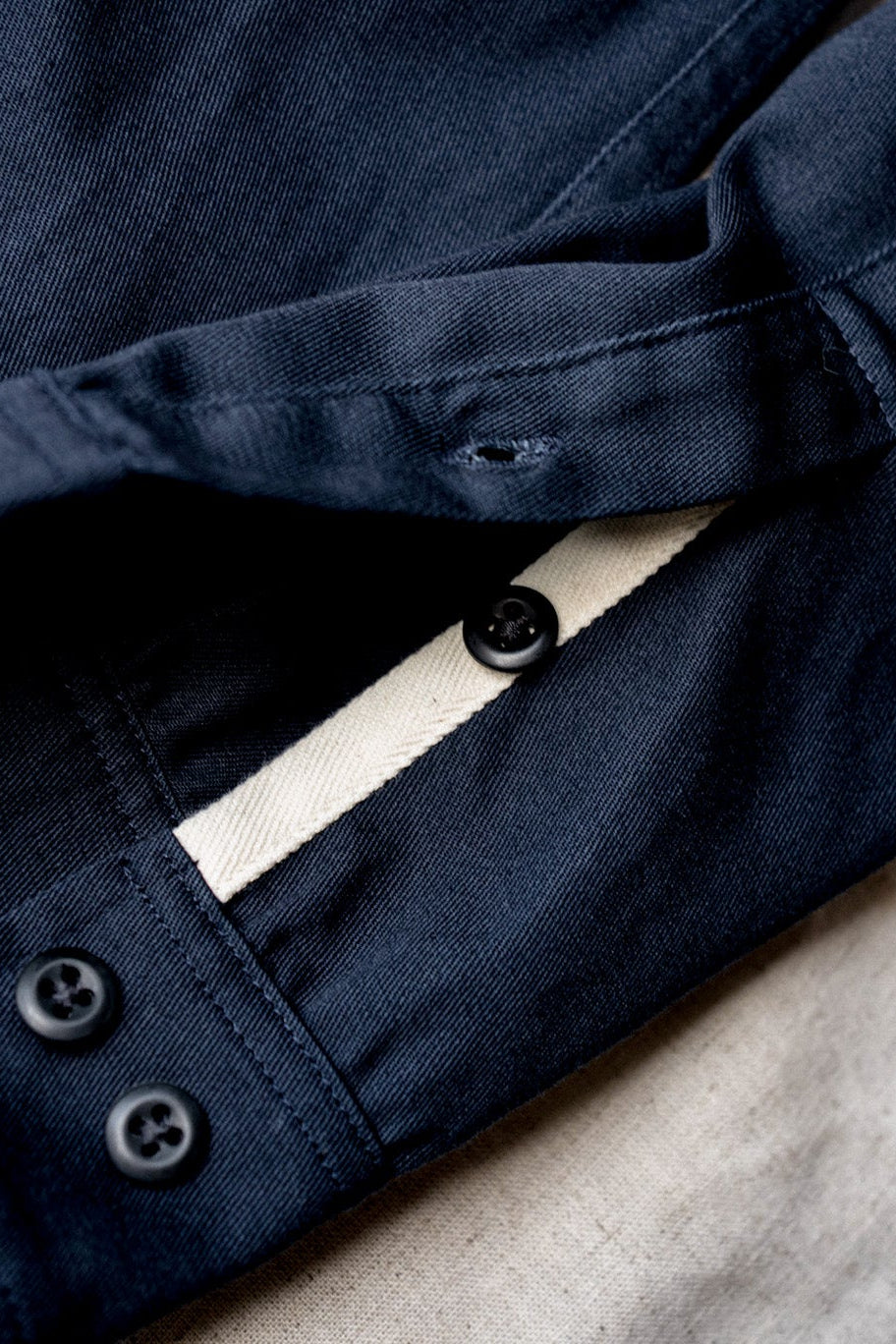 Buttoned cuff and ecru placket tape detail on a women's navy cotton overshirt.
