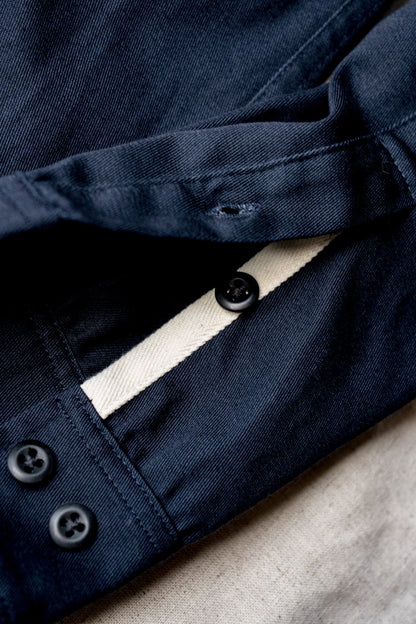 Buttoned cuff and ecru placket tape detail on a women's navy cotton overshirt.