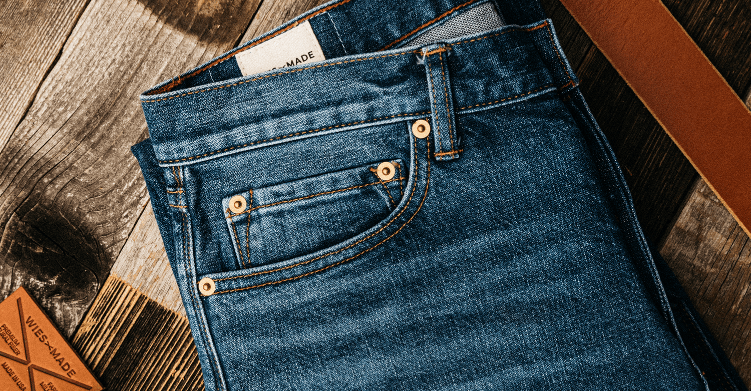 14oz denim jeans on a wooden table next to a leather belt