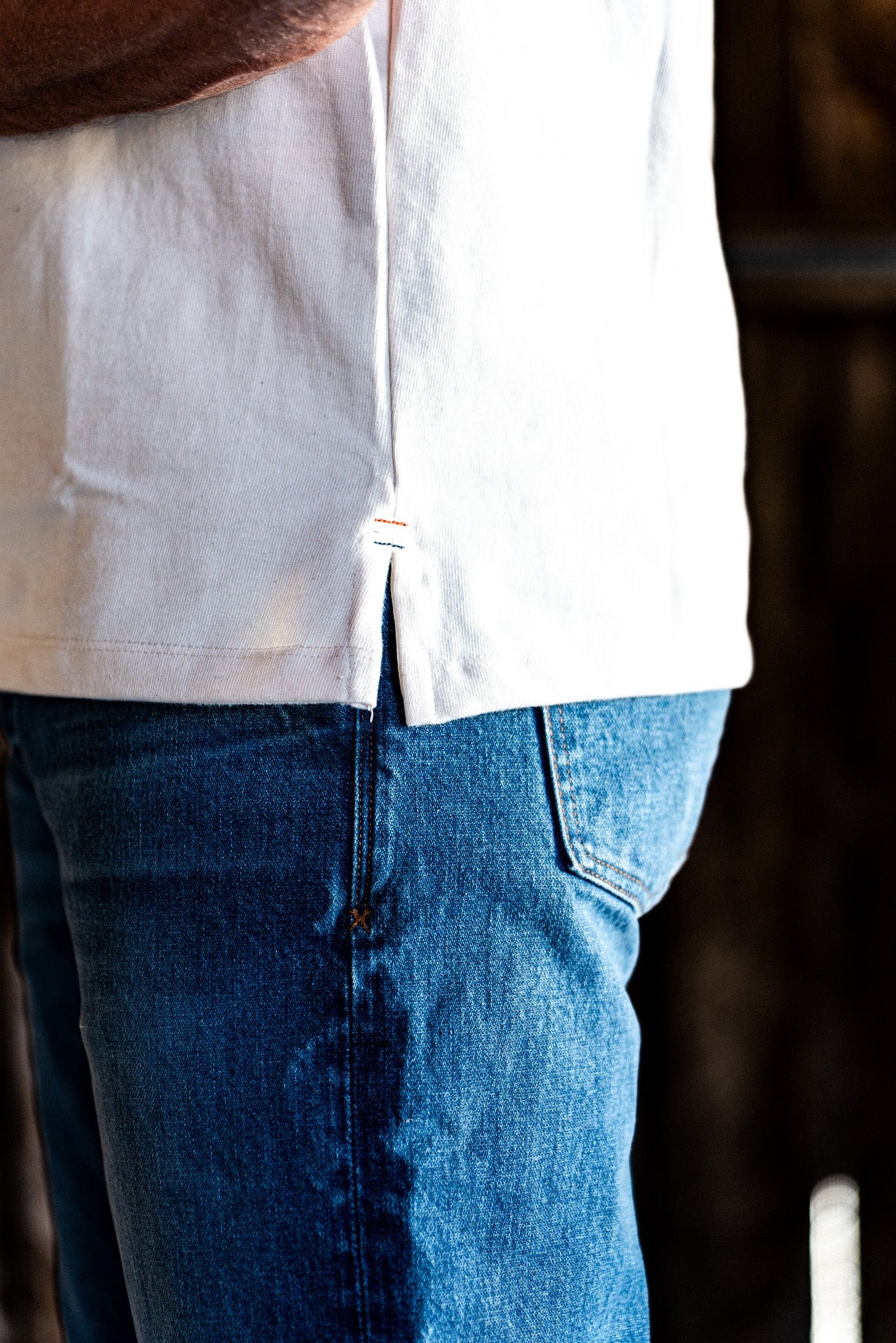 Close-up of the front pocket and topstitching on light wash American made denim worn with a white t-shirt hem.