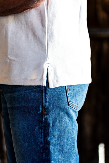 Close-up of the front pocket and topstitching on light wash American made denim worn with a white t-shirt hem.