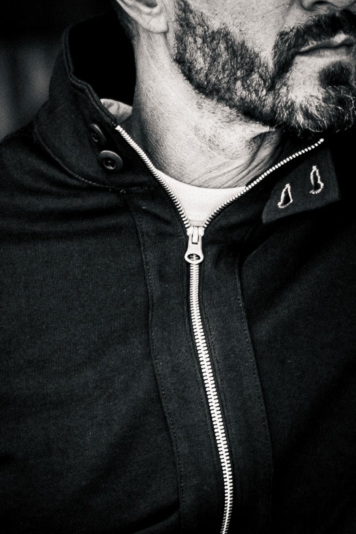 Close-up black and white detail of the zipper and snap collar on a men's moto jacket